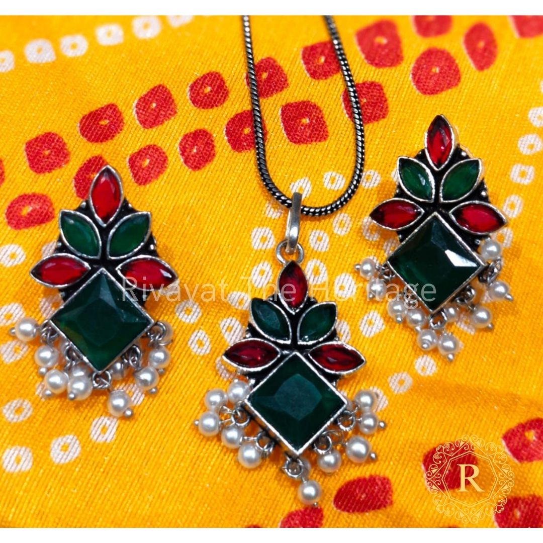 Emerald green German silver oxidized jewelry set with Monalisa stones featuring handcrafted earrings and pendant with pearl clusters on yellow traditional fabric background