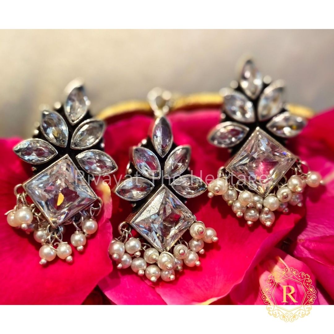 Manika crystal floral oxidized German silver earrings and pendant set on pink fabric background