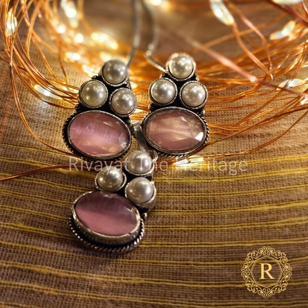 Handcrafted German silver oxidized earrings and pendant set with rose quartz Monalisa stones on golden fabric background
