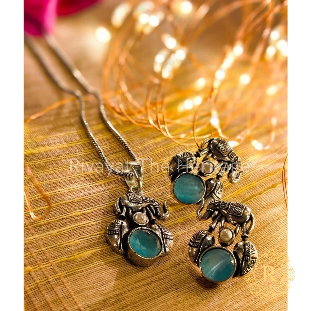 Handcrafted German silver elephant pendant and earrings set with turquoise Monalisa stones on wooden background - Rivayat Heritage jewelry