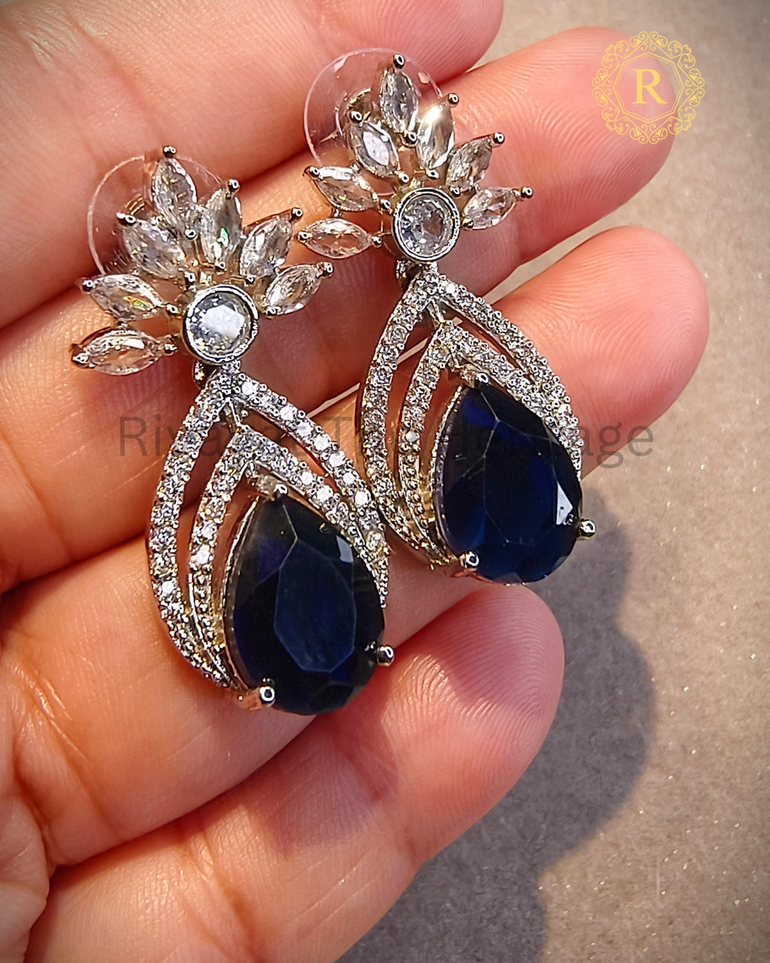 Royal blue zircon diamond pear drop earrings held in hand showing sparkle detail