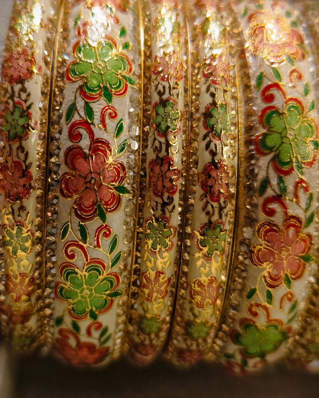 Close-up of white Meenakari bangles with pink and green floral enamel and kundan stone border