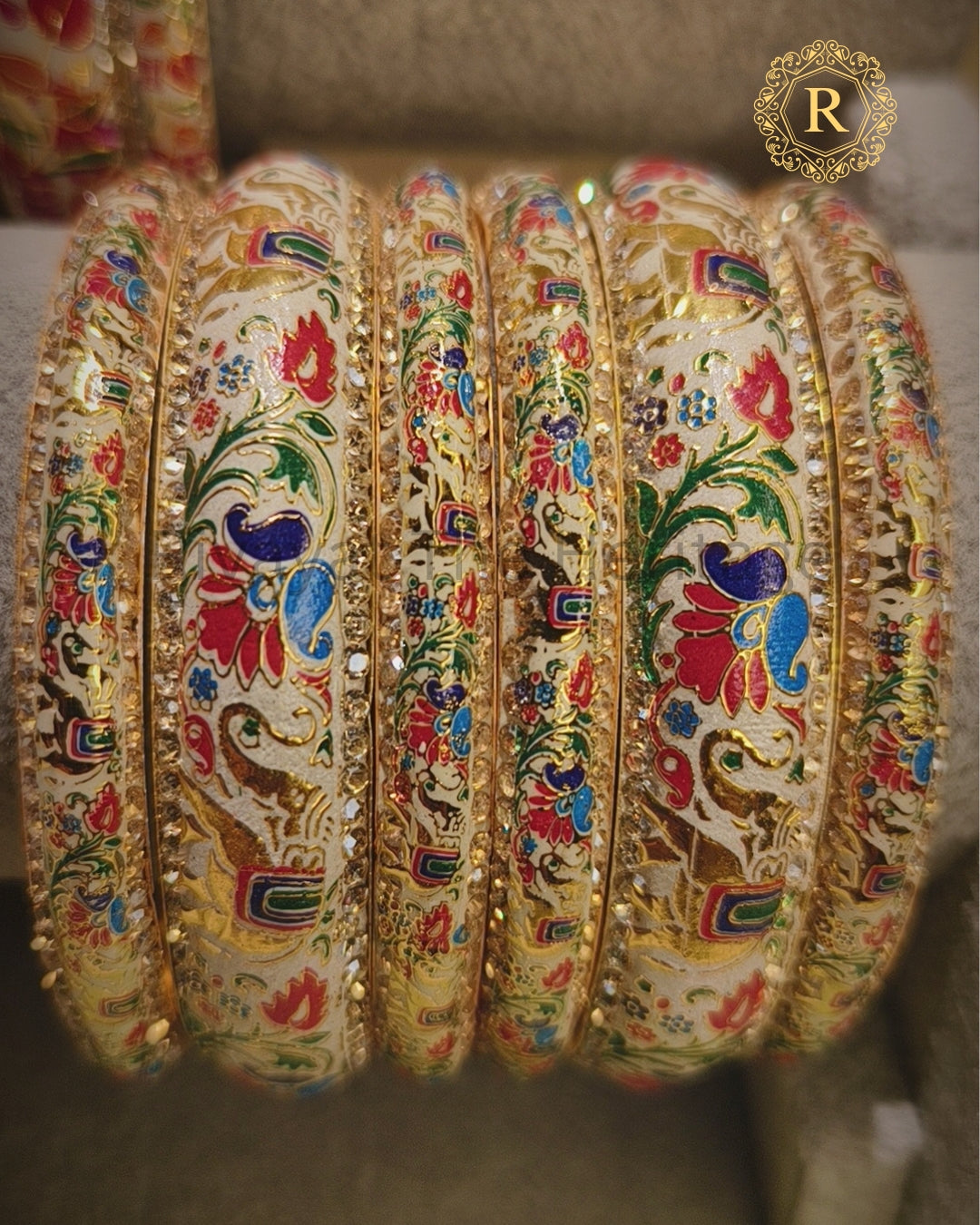 Set of ivory Meenakari kadaa bangles with traditional peacock and floral design, gold-toned finish and stone detailing