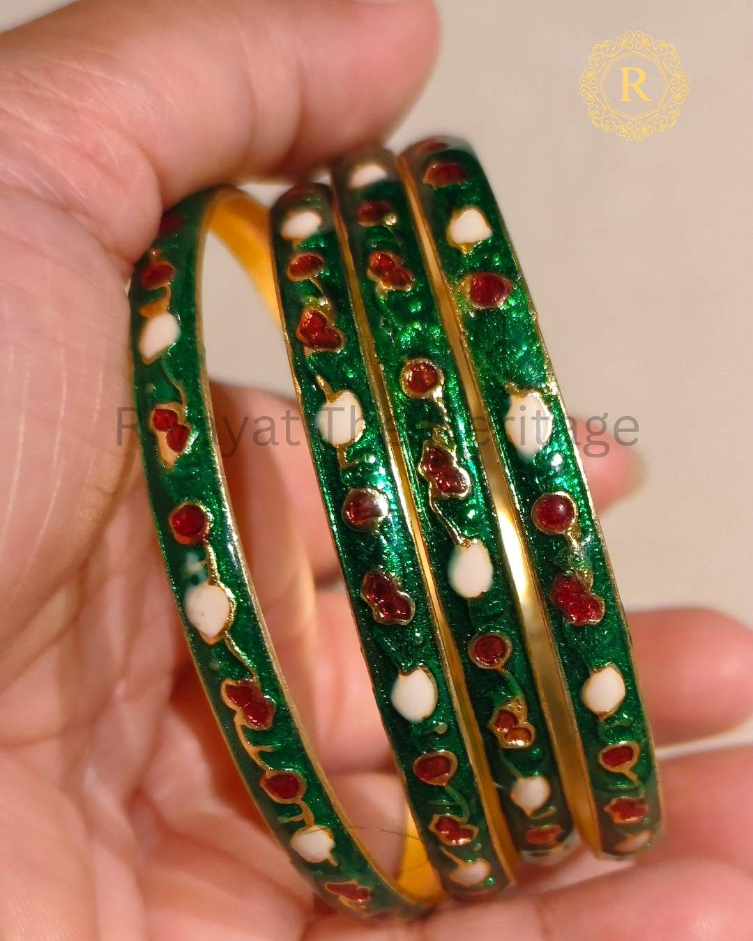 Green Meenakari enamel bangles set of 2 with red and white motifs, gold-tone finish, held in hand