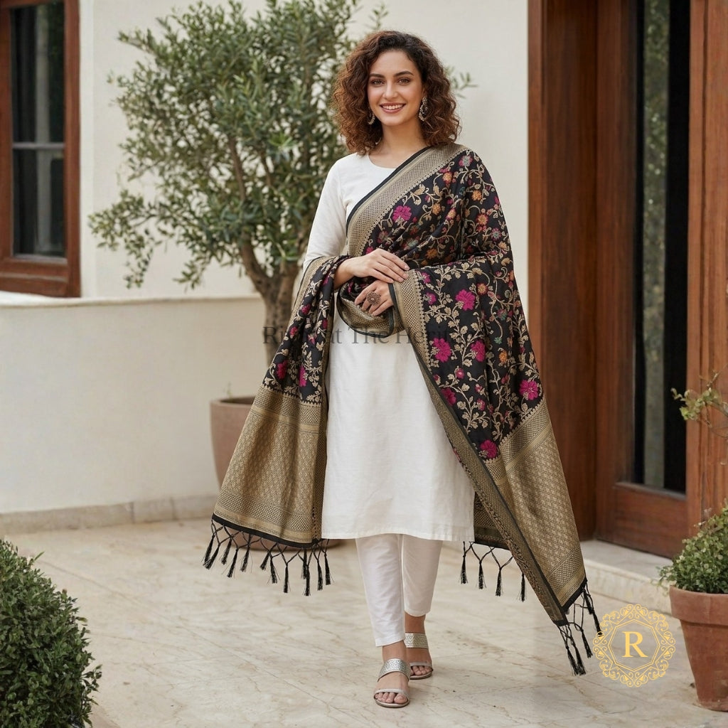 Woman wearing a black Banarasi Art Silk dupatta with multicolour floral jaal and antique gold zari border, draped over a white salwar suit