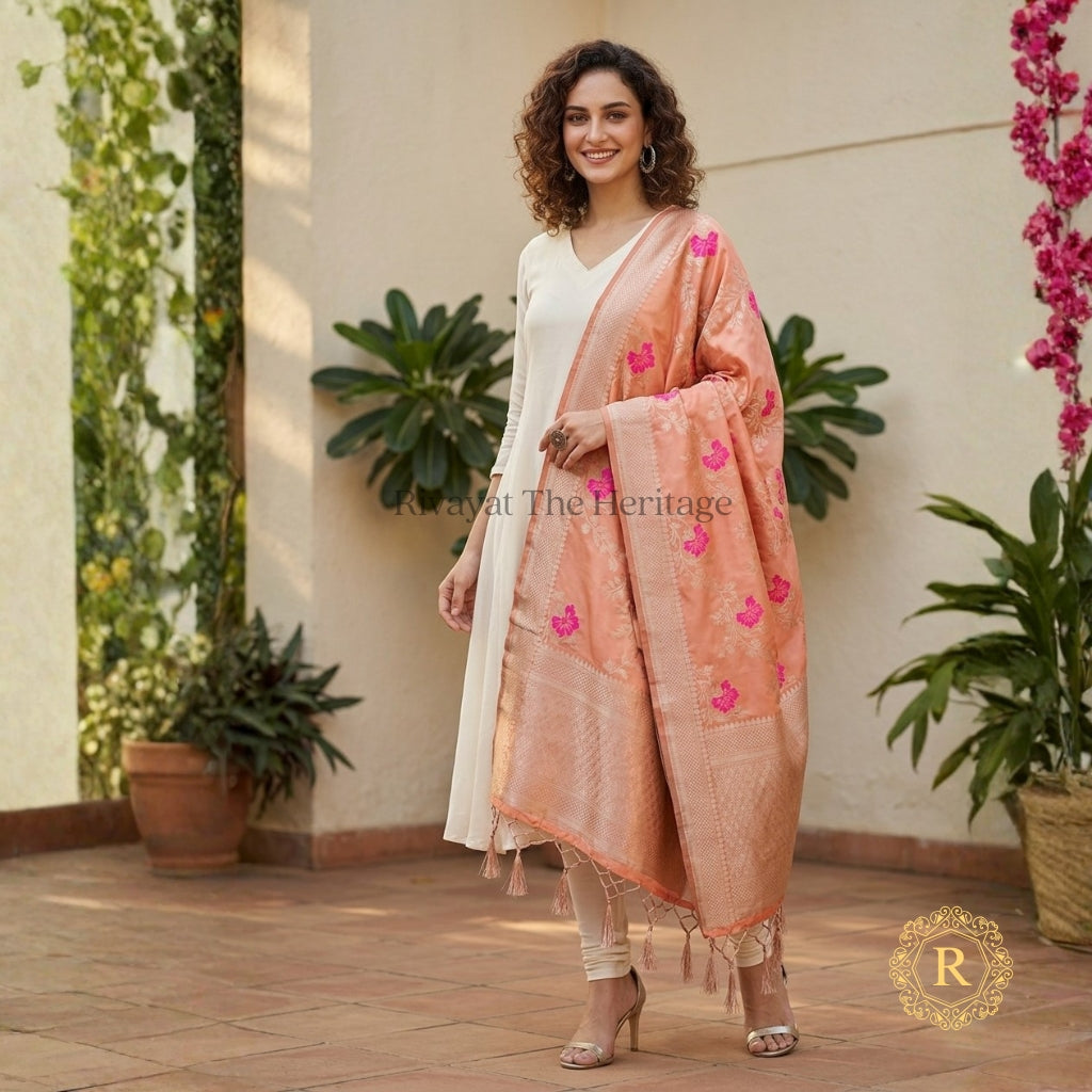 Woman wearing peach Banarasi art silk dupatta with pink floral motifs and gold zari border over white kurta set — Rivayat The Heritage