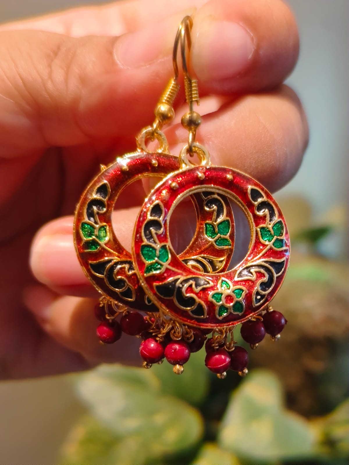 Pair of authentic Indian red Meenakari chandbali earrings with intricate enamel work and dangling red bead drops from Rivayat's Manika Collection