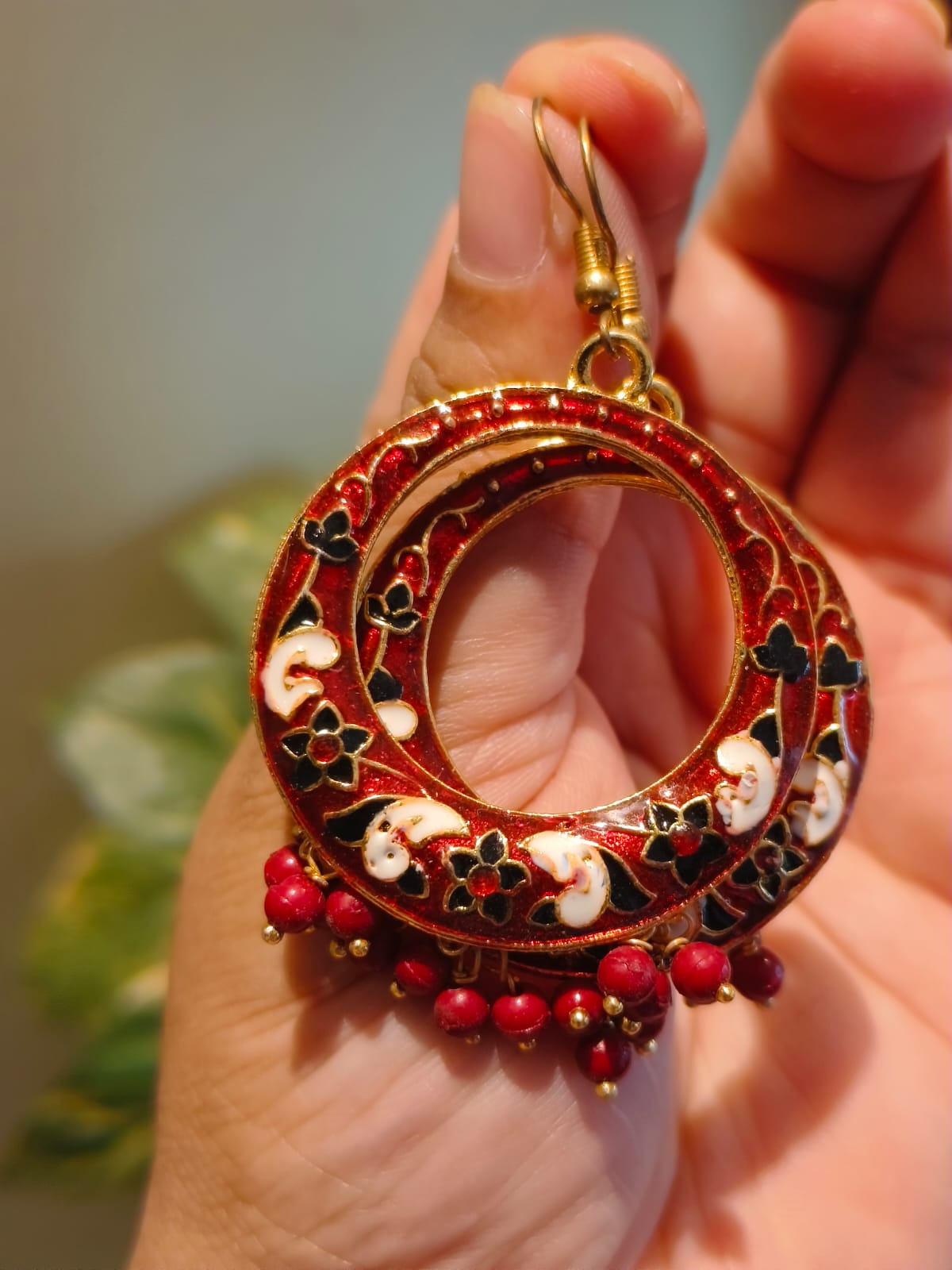Close-up of red Meenakari hoop earring showing intricate floral enamel work and red bead drops — Rivayat Heritage