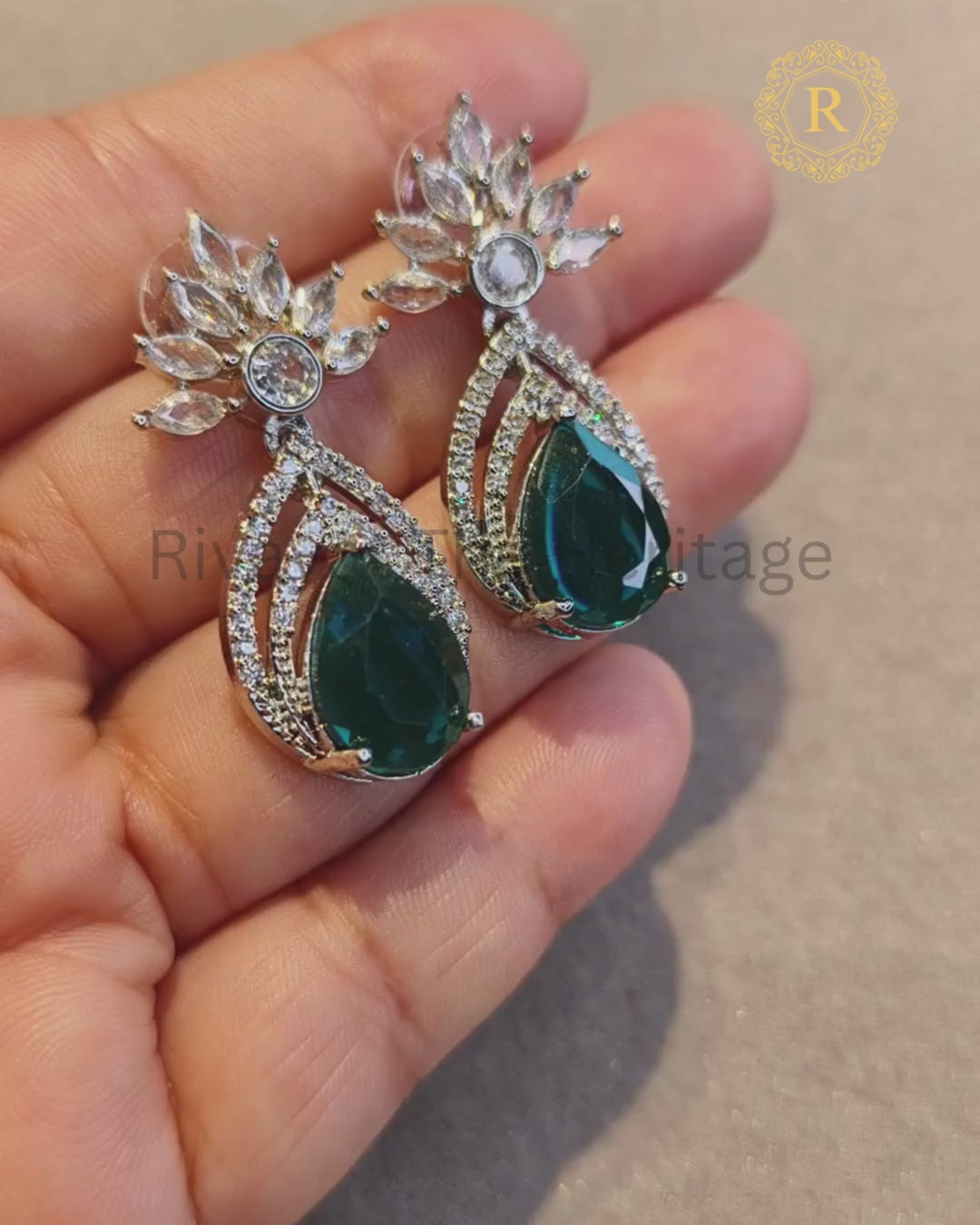 Video showcasing emerald zircon diamond drop earrings with silver rhodium finish, sparkle detail in hand